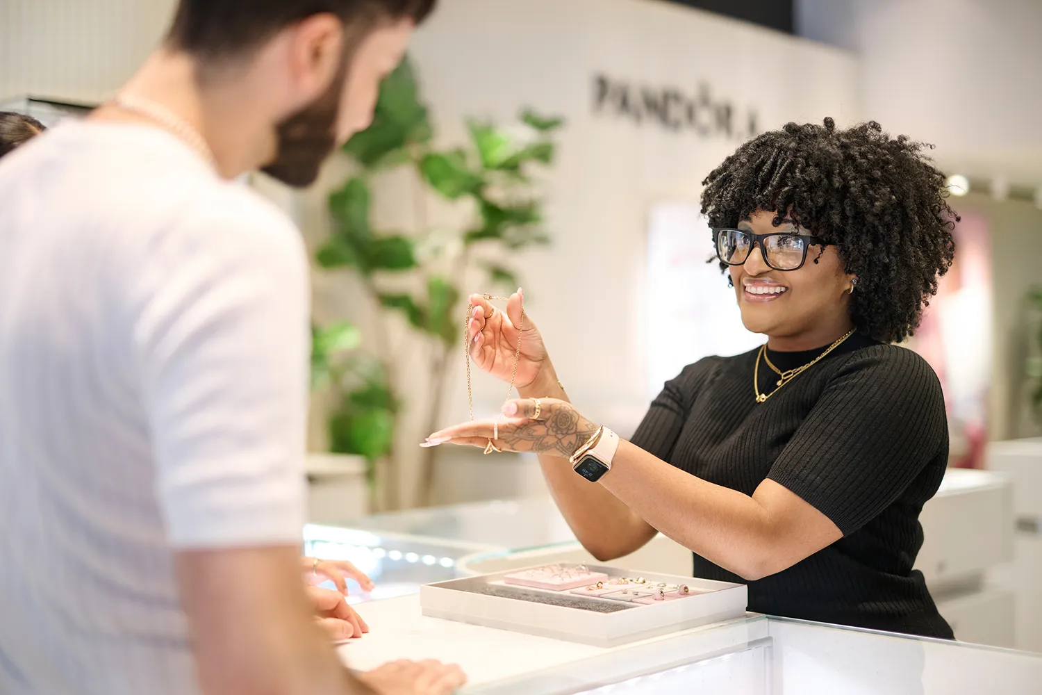 A Pandora store employee shows a necklace to a customer in this overview image.