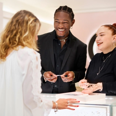A pair of Pandora employees help a customer choose a piece of jewlery