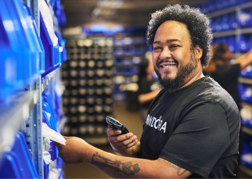 A man taking inventory in a warehouse with an electronic scanner