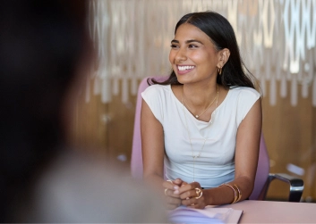 Smiling woman seated at a table with blurred background