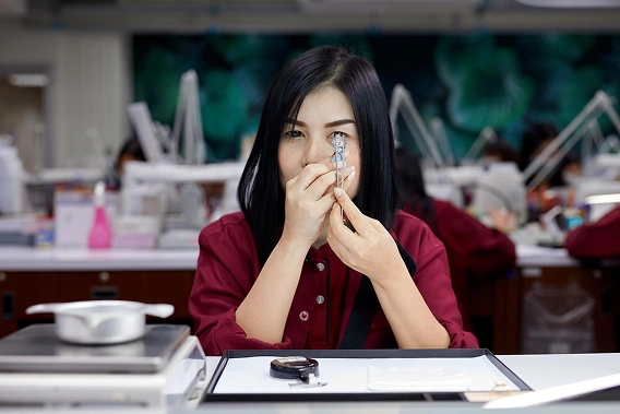 A smiling woman wearing a black t-shirt with "BE LOVE" printed in pink and a man wearing a black t-shirt stand in a jewelry store.