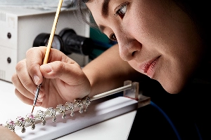 Pandora employees work together at a conveyor belt packaging jewelry