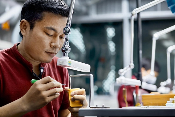 Four smiling staff members in a Disney x Pandora store stand behind a glass display case showing Pandora jewelry.