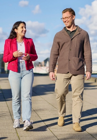 A smiling Pandora employee hands a shopping bag to a customer in a jewelry store.