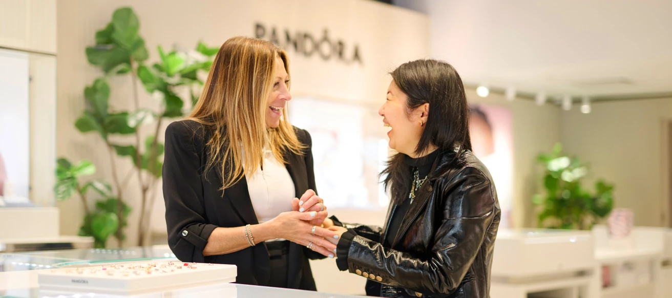A pair of women an indoor setting looking at each other smiling and laughing